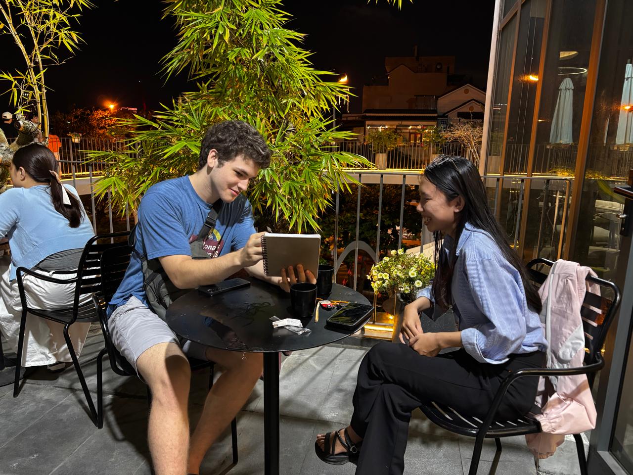 Two members practicing together at an outdoor table during the May 1, 2026 language exchange in Da Nang.